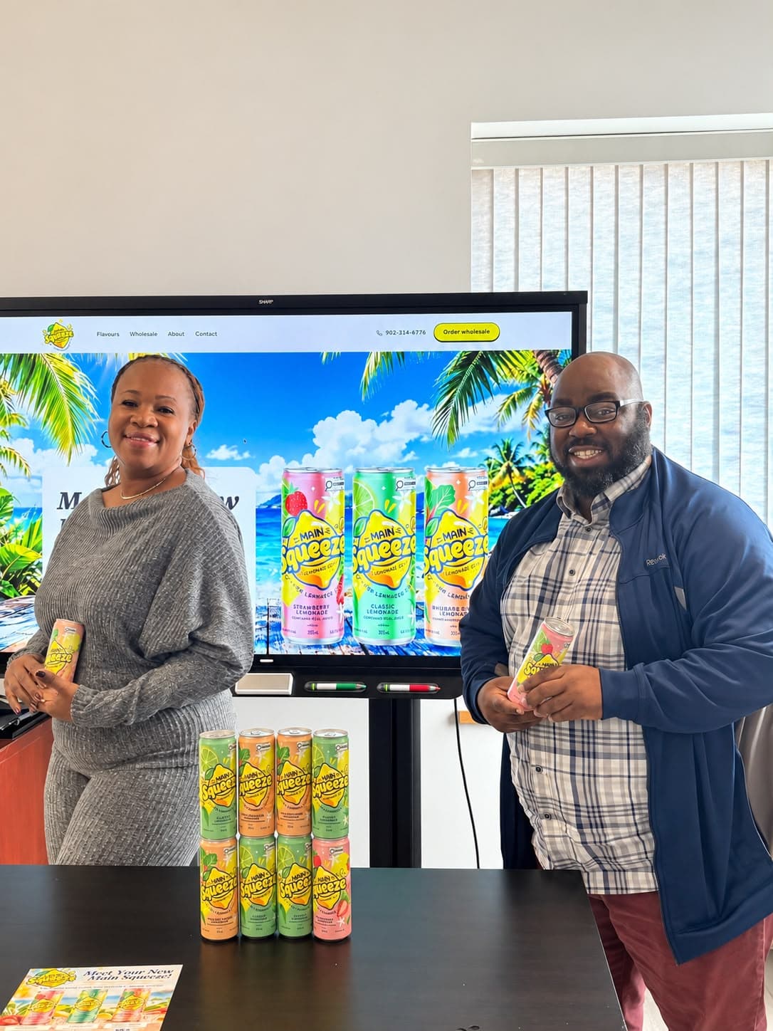 Co-founders Lorinda Skyers and Jared Whyms holding Main Squeeze cans in front of the Main Squeeze website